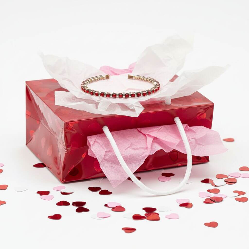 Red Crystal Bangles Are This Season's Power Move displayed in a red gift box with heart-shaped confetti.