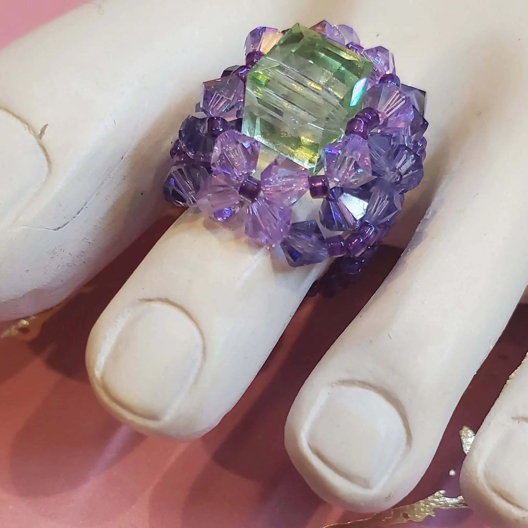 Handmade Beaded Swarovski Crystal Cocktail Rings featuring a large green crystal and purple beads on a finger.