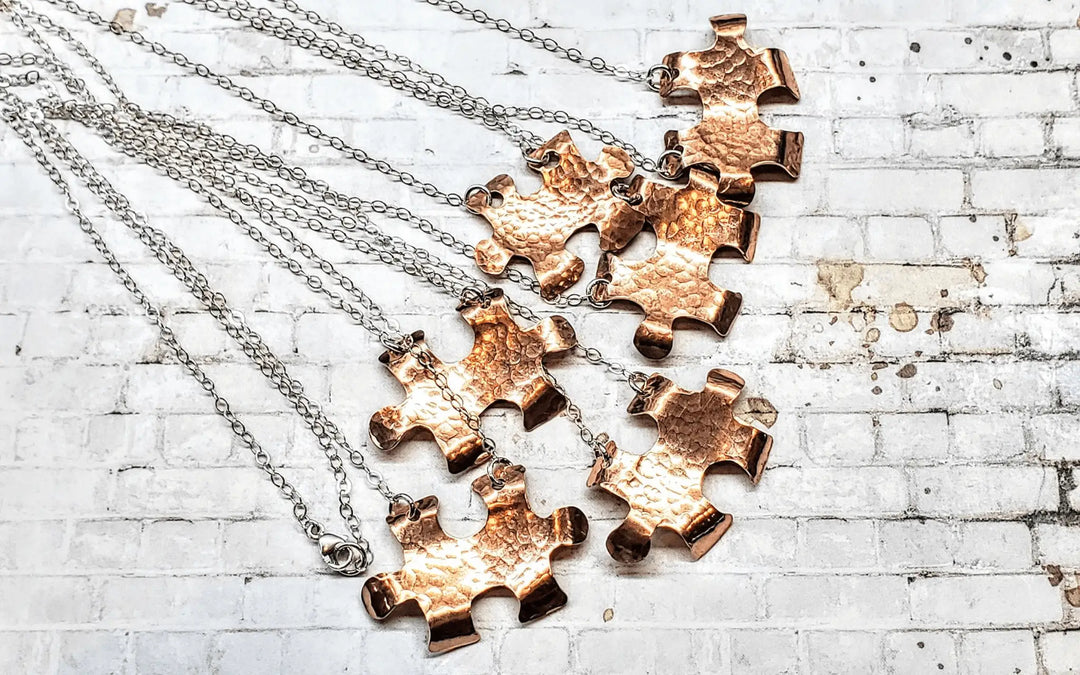 Handmade Autism Awareness jewelry featuring copper puzzle piece necklaces on silver chains.