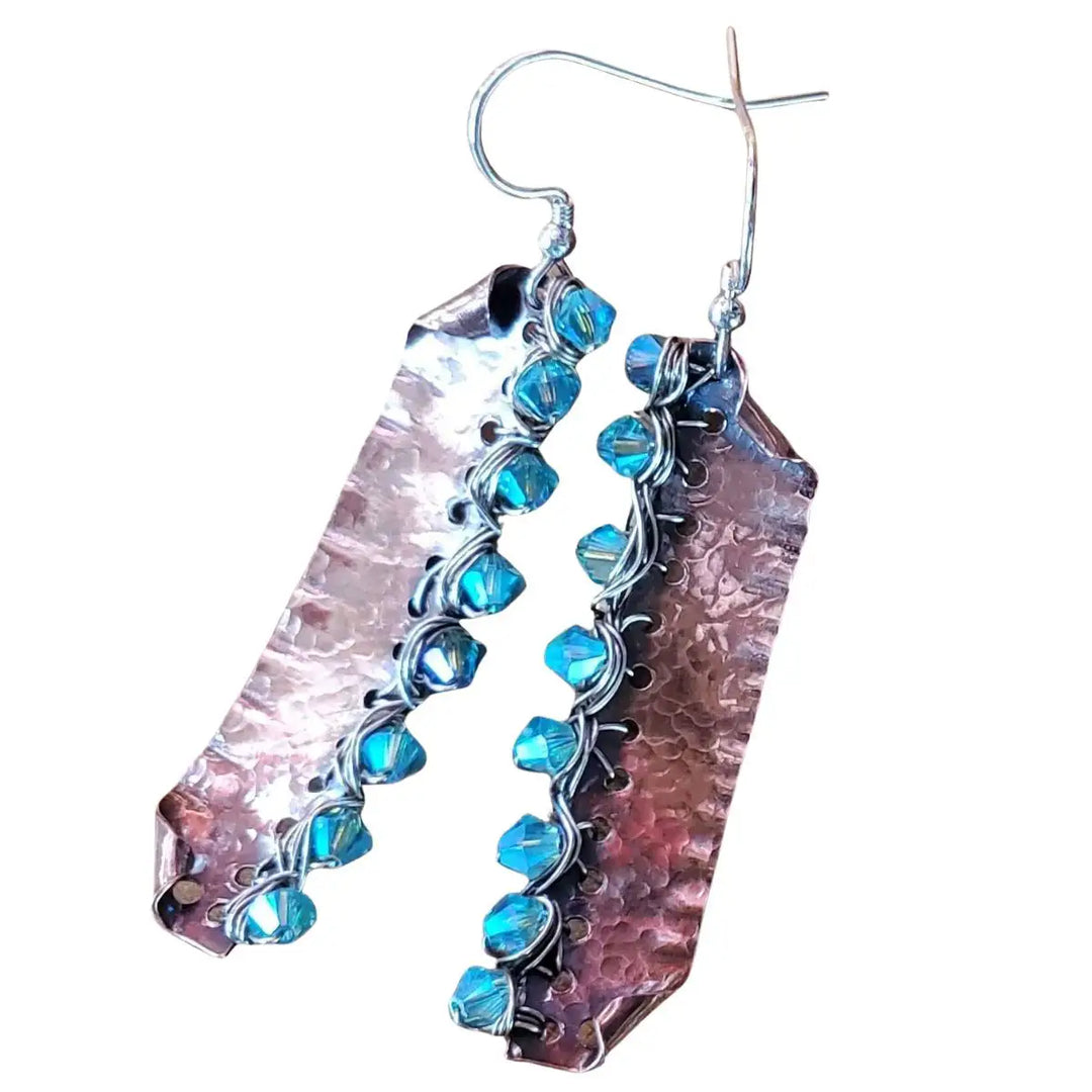 A joyful woman wearing colorful earrings from the handmade in style earrings collection, smiling outdoors.