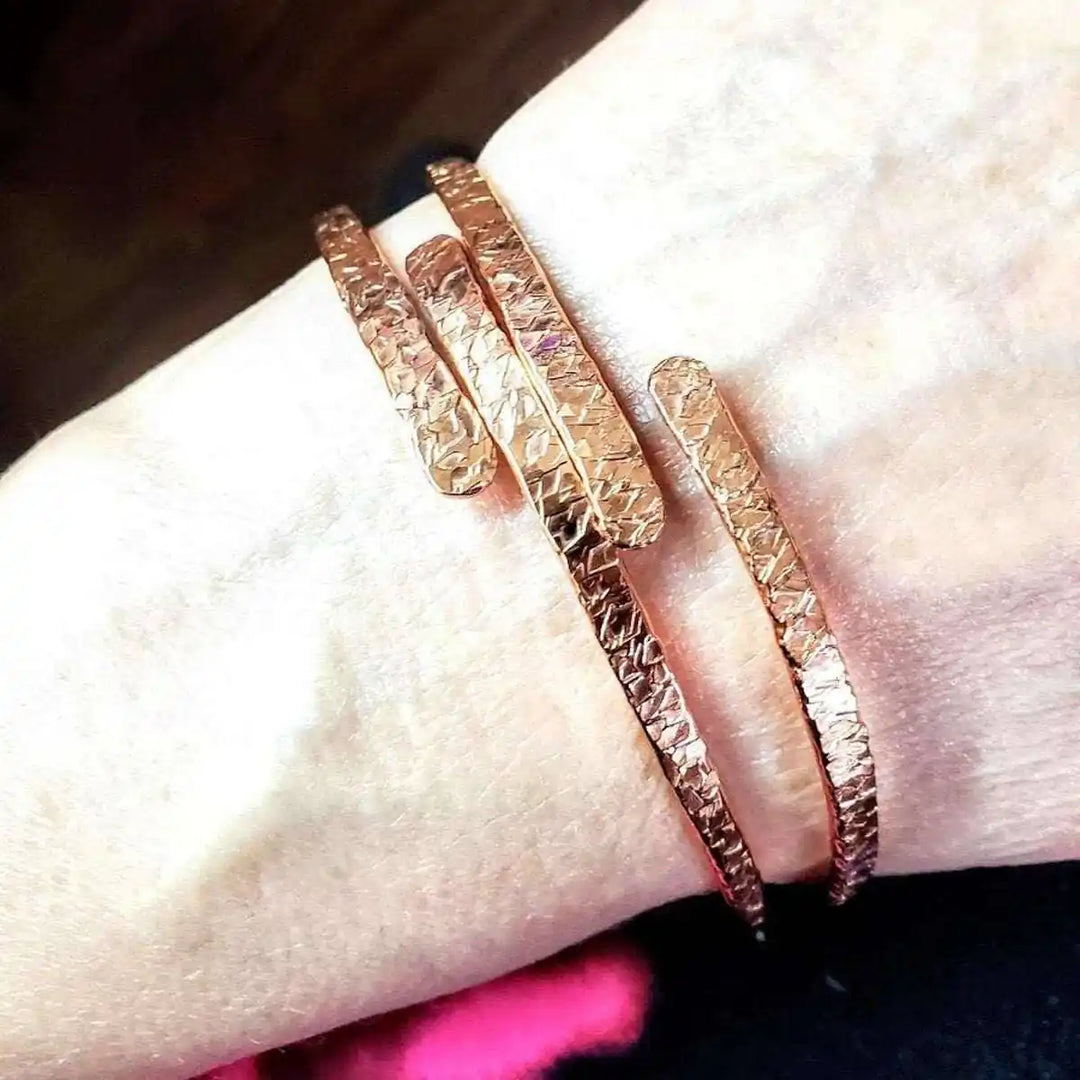 Unisex 8 Gauge Adjustable Hammered Copper Overlap Bangle worn on wrist, showcasing hammered texture and adjustable design.