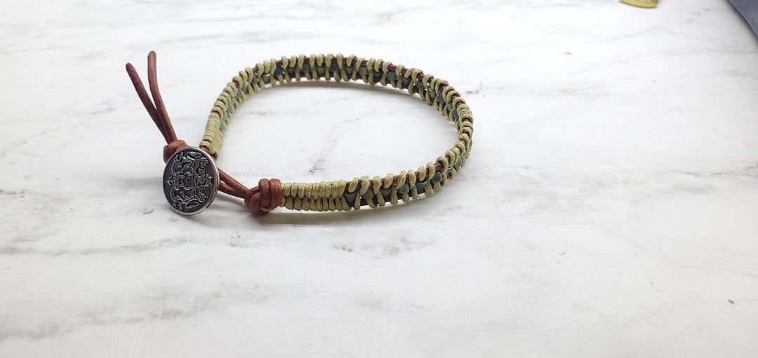 A  two tone leather wrap seed bead button bracelet laying on marbled background