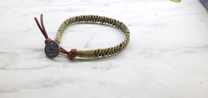 A  two tone leather wrap seed bead button bracelet laying on marbled background