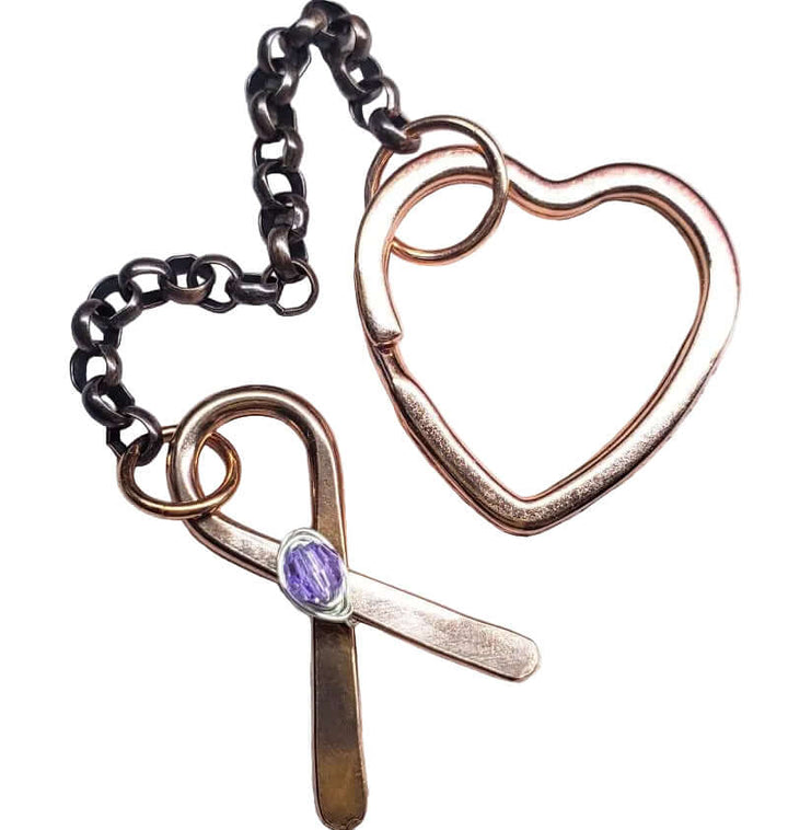 Heart-shaped and cross-shaped jewelry with a purple gemstone on a textured surface
