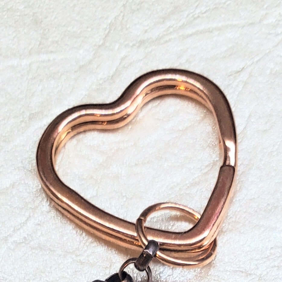 Rose gold heart-shaped keychain on a textured white background