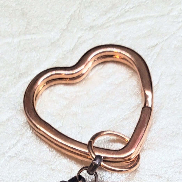 Rose gold heart-shaped keychain on a textured white background