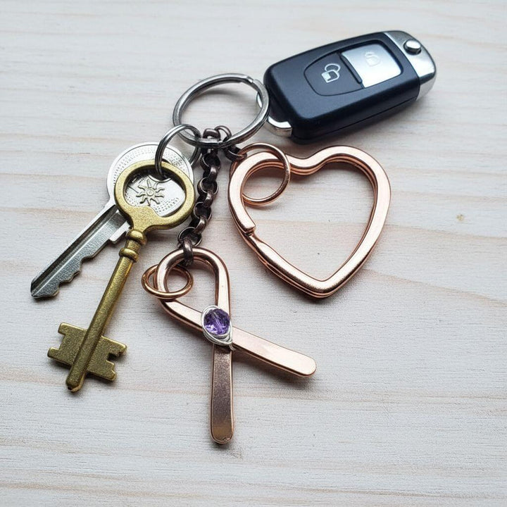 Keychain with heart-shaped keyring, keys, and a car key fob on a light wooden surface