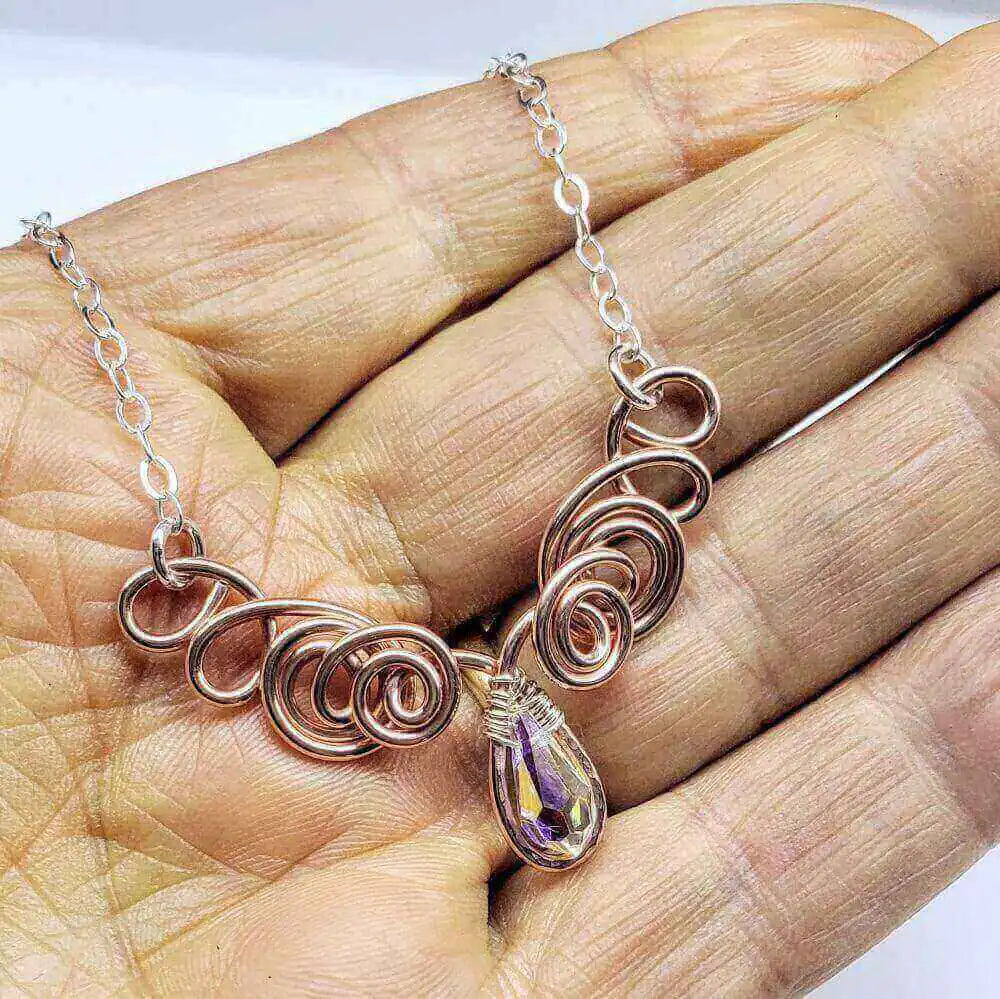 Handmade Sculpted Copper Silver Angel in Flight Necklace displayed on a hand, showcasing its unique design and sparkling details.