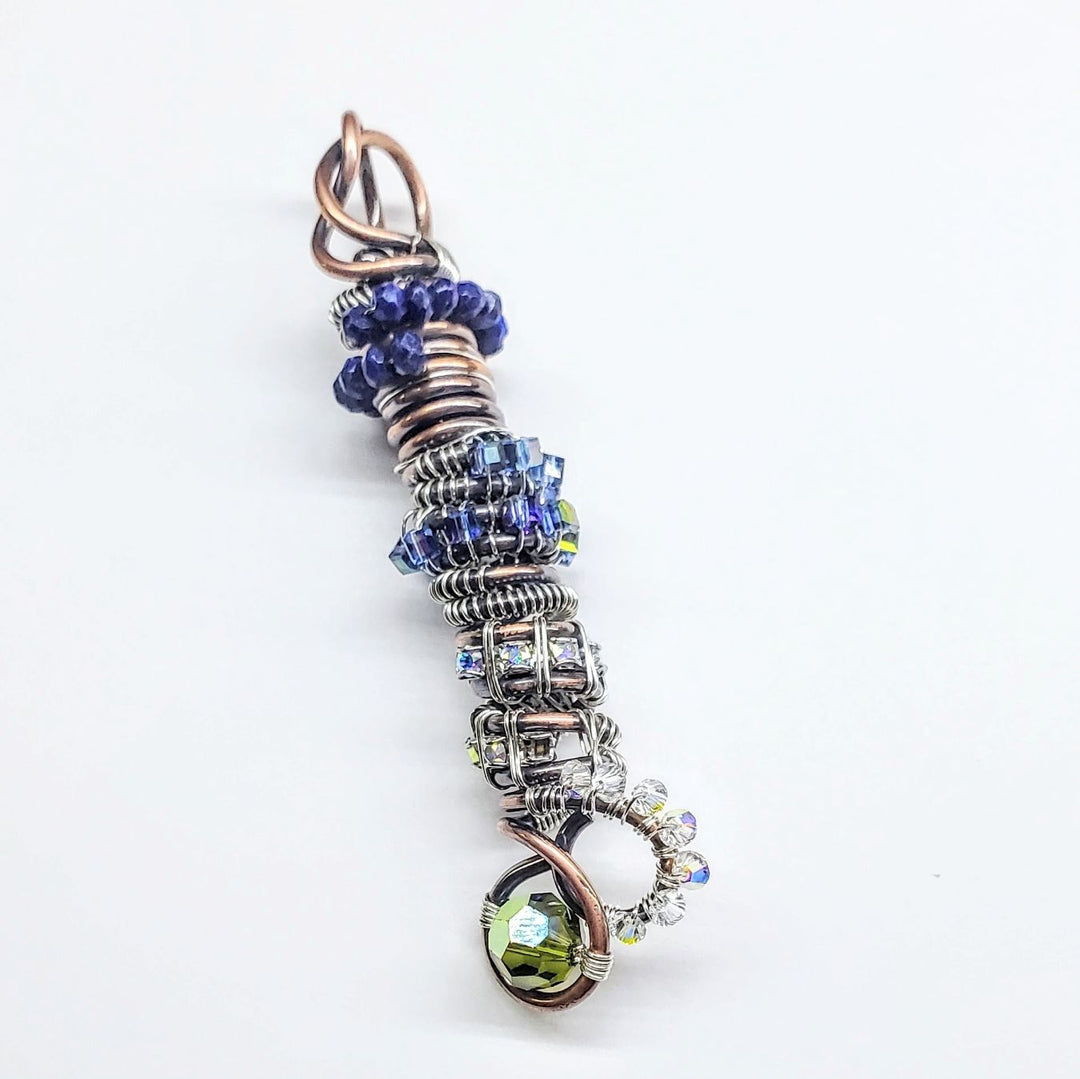 Decorative pendant with blue and green beads on a white background