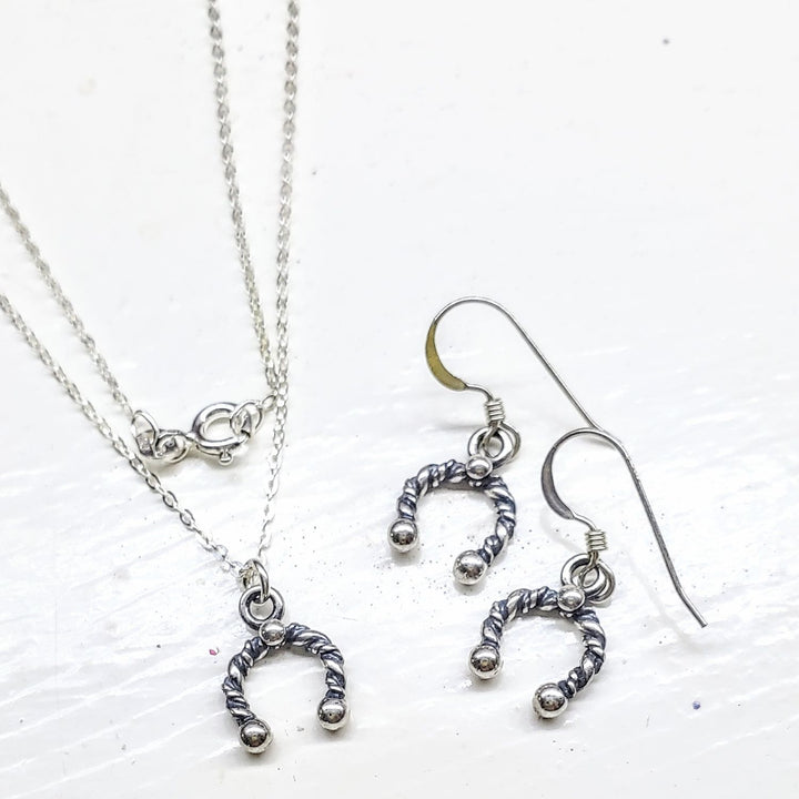 Handmade sterling silver horseshoe jewelry set featuring necklace and earrings in a stylish design.