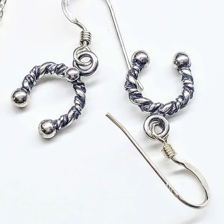 Handmade sterling silver horseshoe jewelry featuring twisted horseshoe earrings in artisan design.