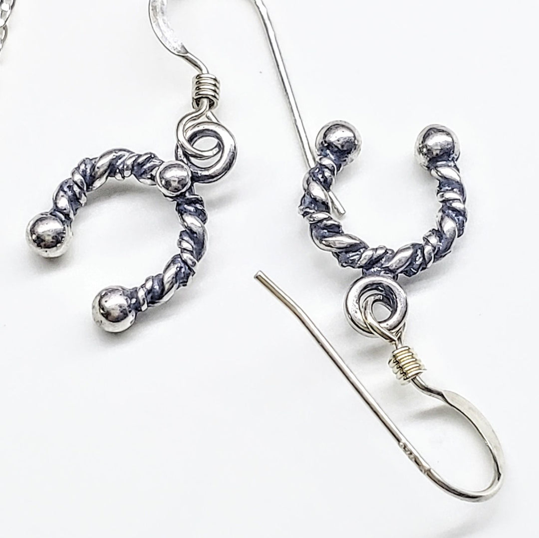 Handmade sterling silver horseshoe jewelry earrings featuring a twisted design and elegant details.