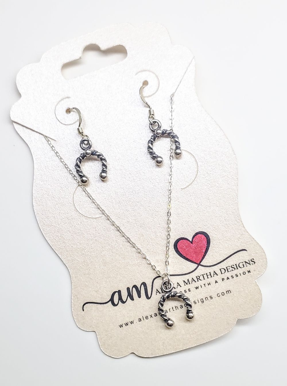 Handmade sterling silver horseshoe jewelry set with earrings and necklace on display card.