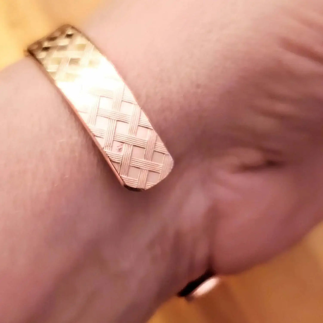 Close-up of a His and Her Copper Embossed Weave Cuff 16 Gauge bracelet on a wrist, showcasing its intricate design.