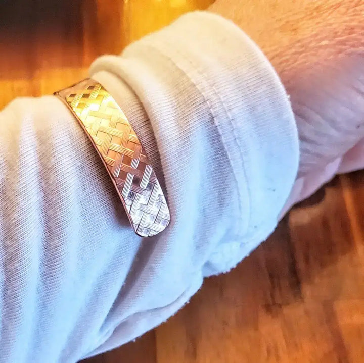His and Her Copper Embossed Weave Cuffs 16 Gauge showcased on a wrist in a cozy setting.