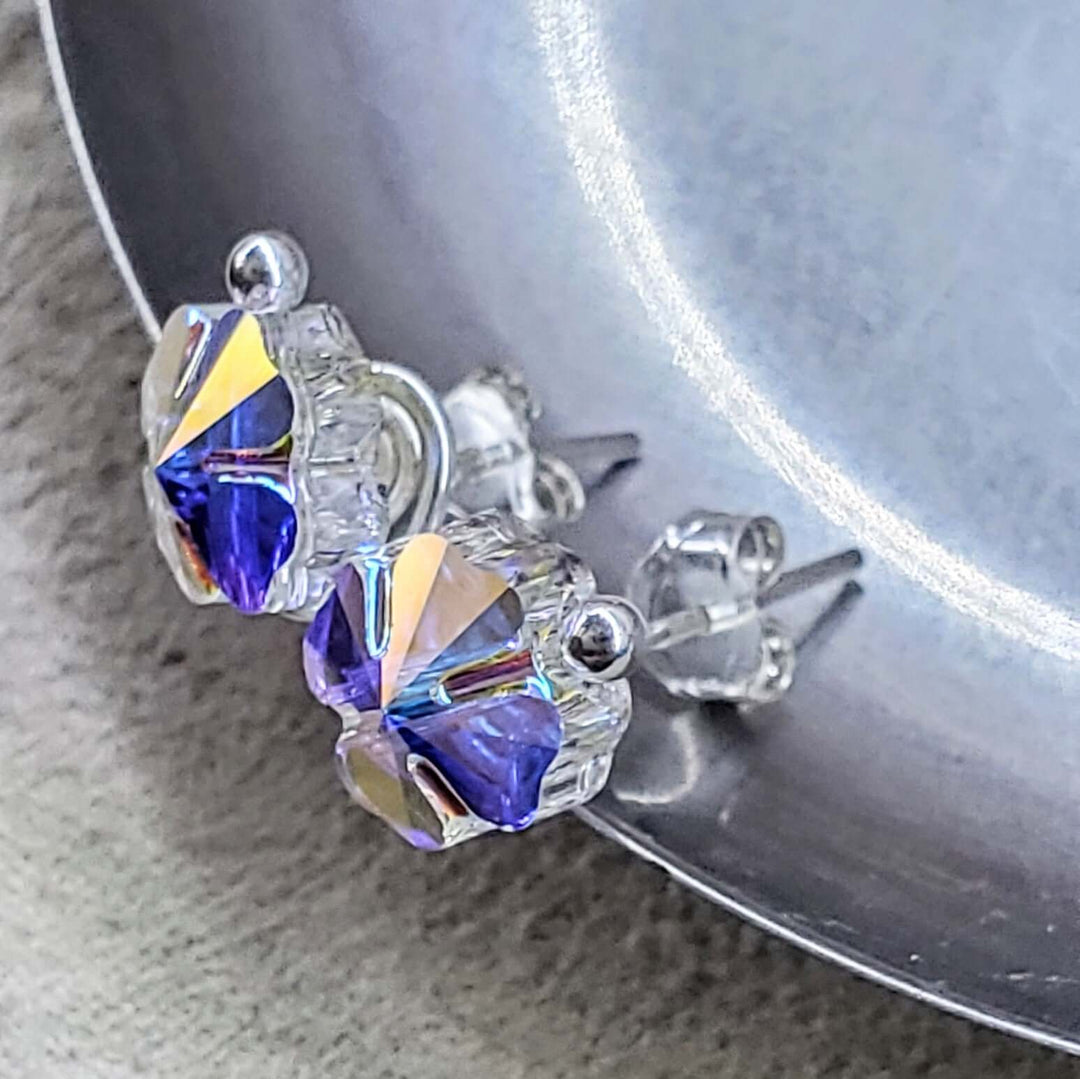 8mm Crystal Clover Silver Spiral Ear Studs on a silver surface showcasing their sparkle and craftsmanship.