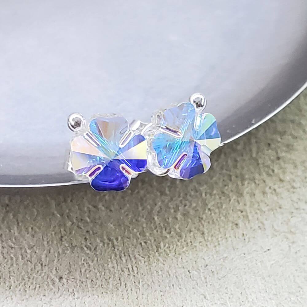 8mm Crystal Clover Silver Spiral Ear Studs on a silver plate, showcasing their sparkling design and craftsmanship.