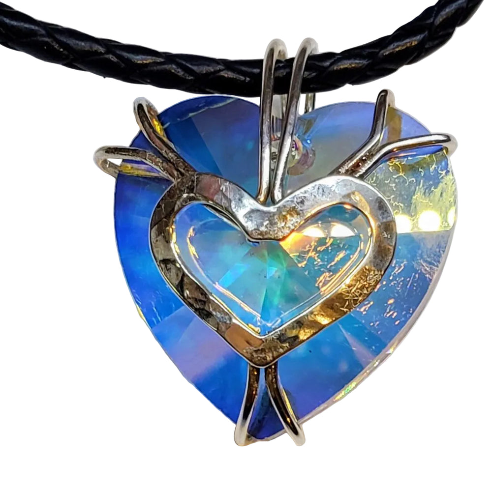 Heart-shaped pendant with blue and gold iridescent center on a black cord against a white background