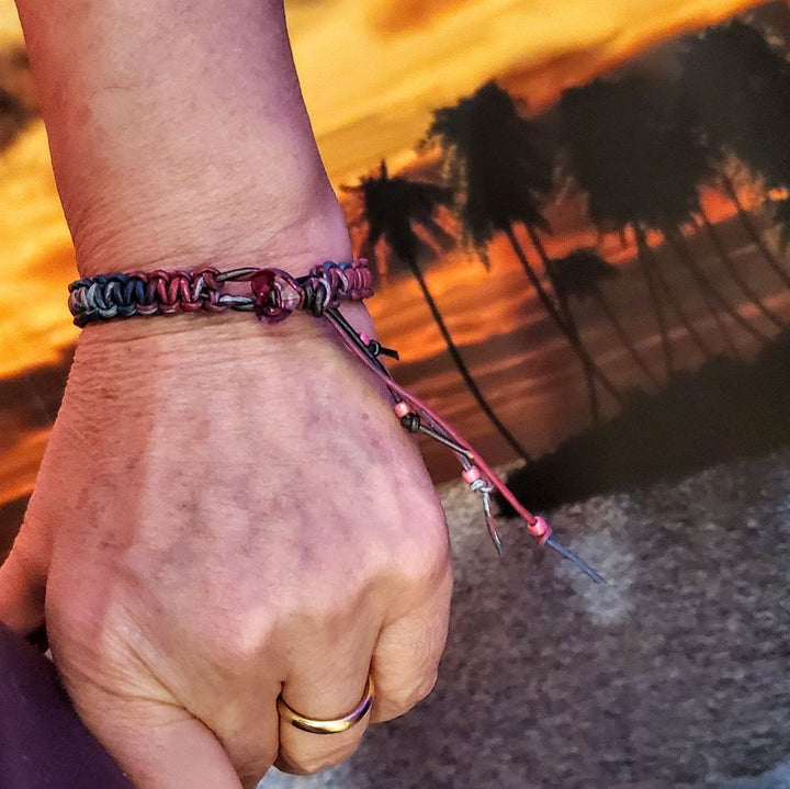 Macrame tie-dye leather Crystal bracelet worn on a wrist, showcasing vibrant colors against a sunset background.