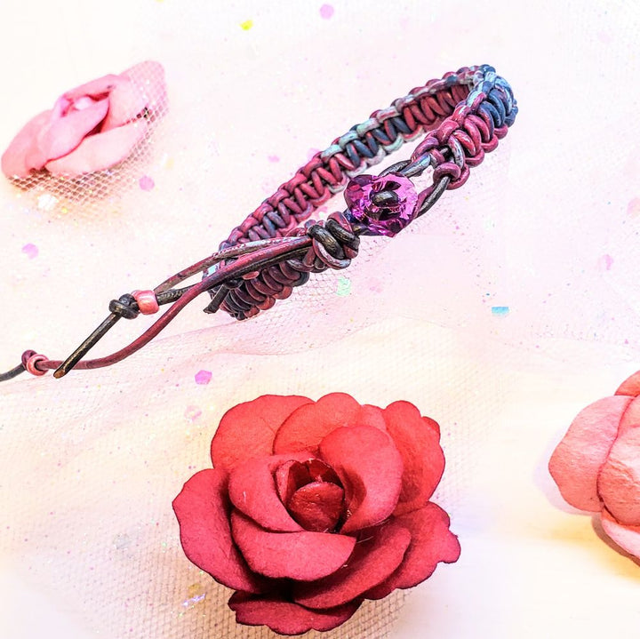 Macrame tie-dye leather Crystal bracelet on a pink background with decorative roses.