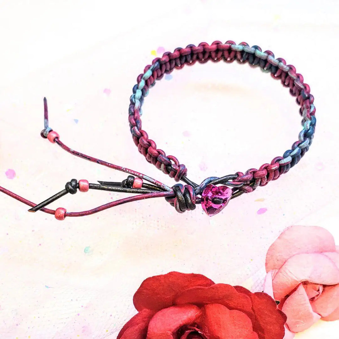 Macrame tie-dye leather Crystal bracelet with vibrant pink, blue, and black colors on a floral background.