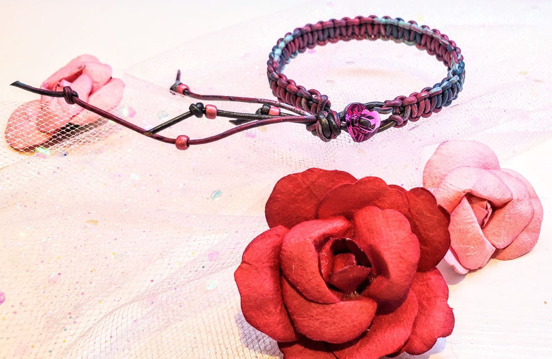 Macrame tie-dye leather Crystal bracelet displayed with pink fabric and red paper flowers.