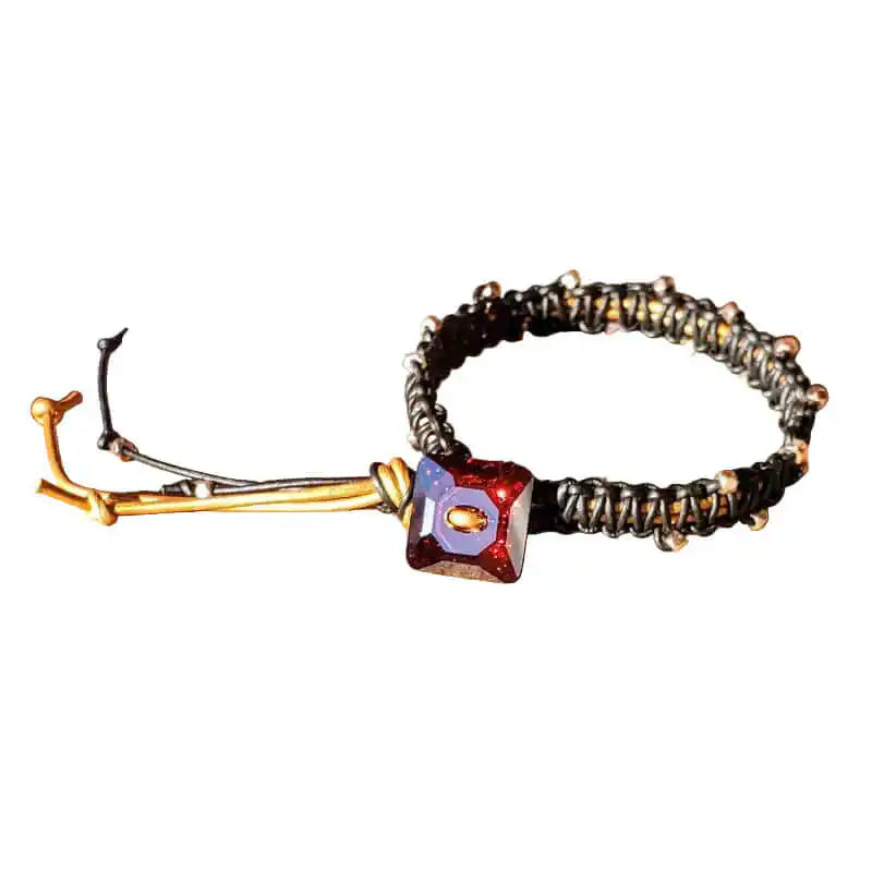 Bracelet with red gemstone and gold accents on a wooden surface