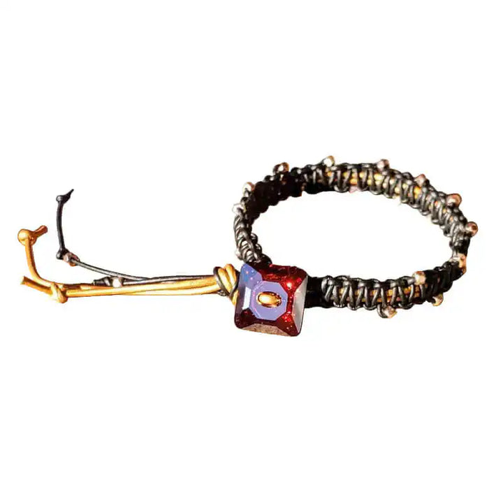 Bracelet with red gemstone and gold accents on a wooden surface