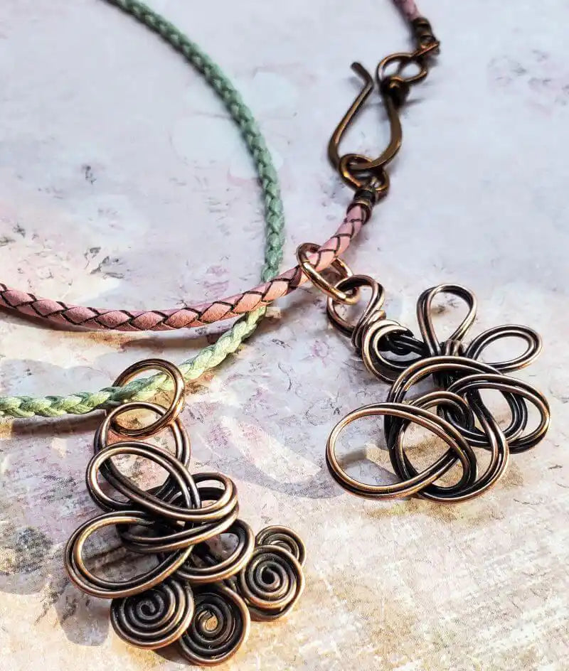 Close-up of Reversible Interchangeable Copper Wire Sculpted Necklaces with intricate designs on braided cords.