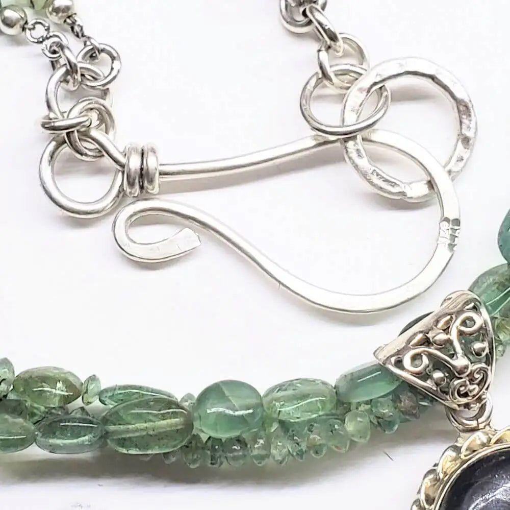 Close-up of clasp detail on Multi Strand Blue Green Silver Bezel Labradorite Necklace, showcasing intricate silver design and green stones.