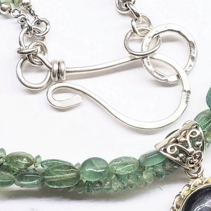 Close-up of clasp detail on Multi Strand Blue Green Silver Bezel Labradorite Necklace, showcasing intricate silver design and green stones.