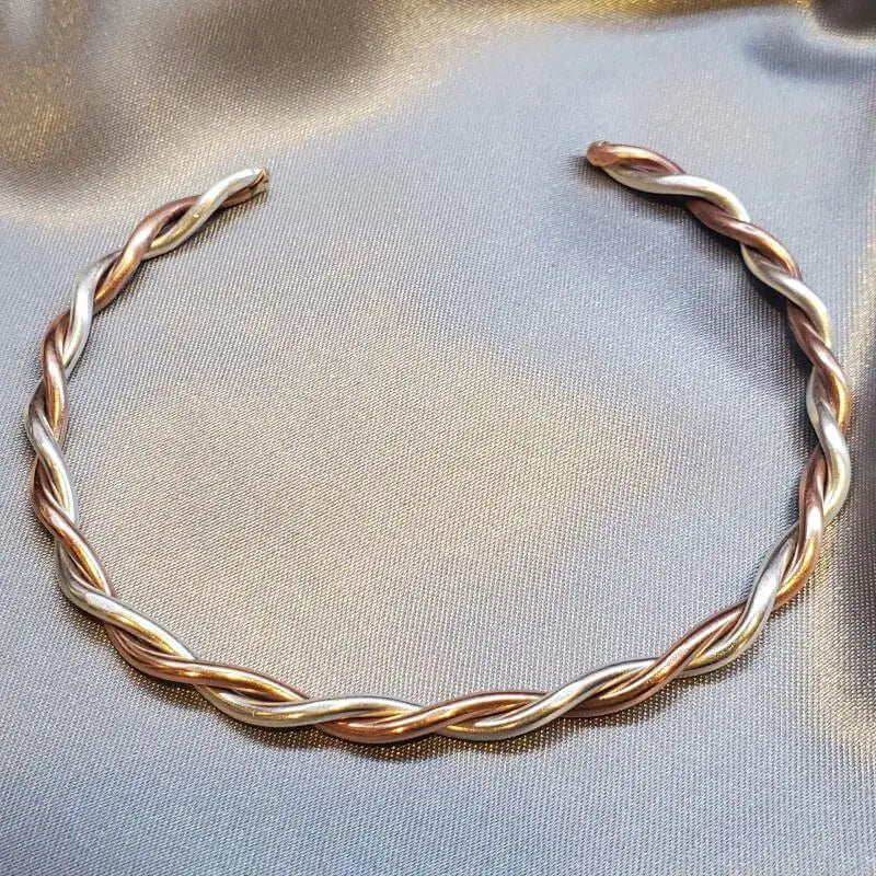 Thick Copper and Sterling Silver Twisted Bangle on a soft fabric background.