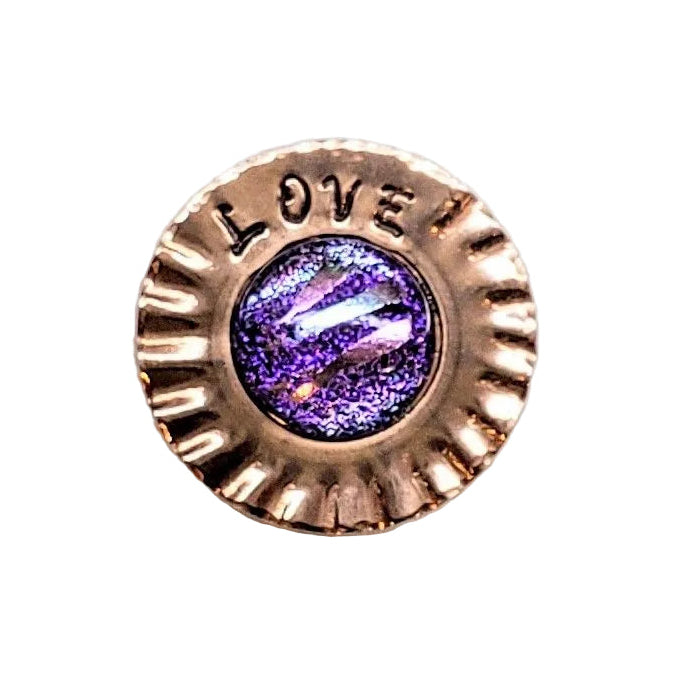 A round, scalloped rose gold button with the word &