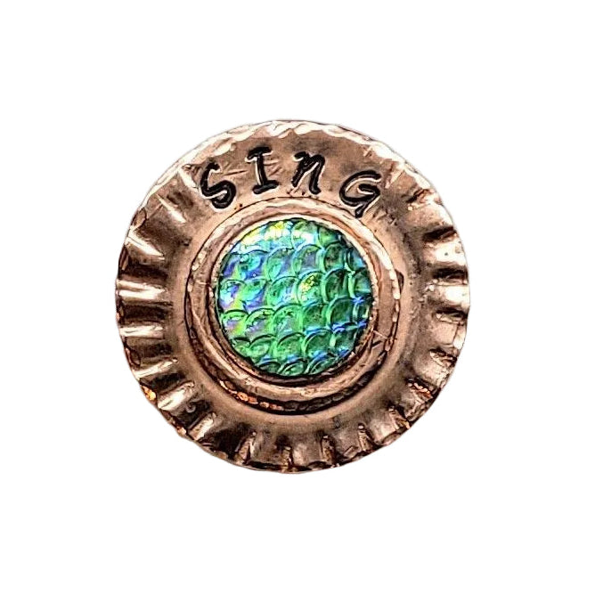 A round copper-colored metal button or stud with a scalloped edge, featuring the word &