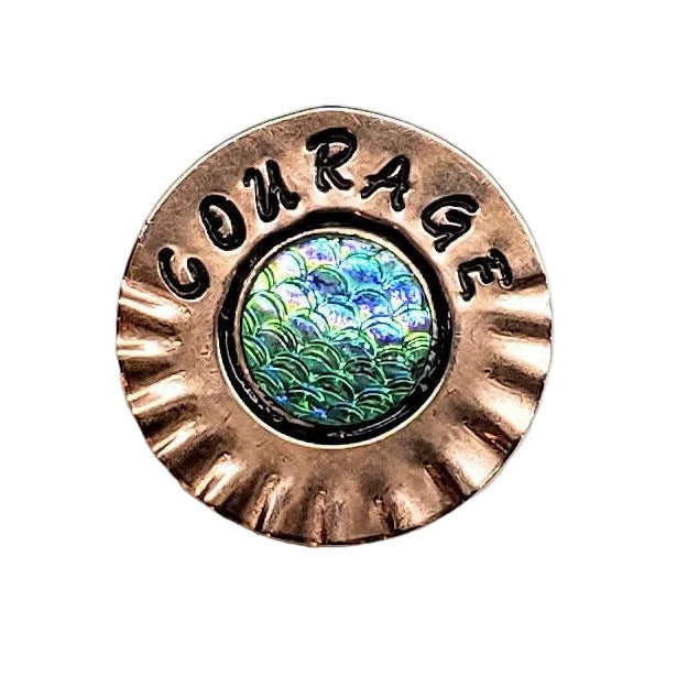 A round copper-toned metal pin with a scalloped edge, the word &