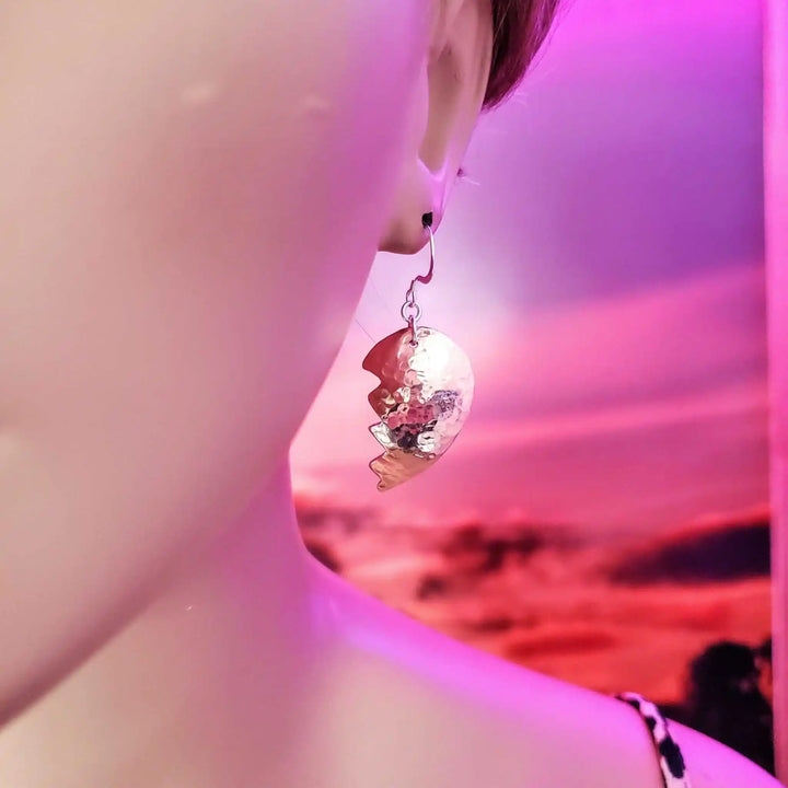 Handmade Sculpted Copper Broken Heart Earrings showcased on a mannequin against a colorful background.