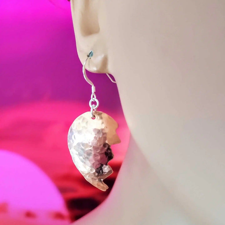 Handmade Sculpted Copper Broken Heart Earrings elegantly displayed on a mannequin ear with colorful background.
