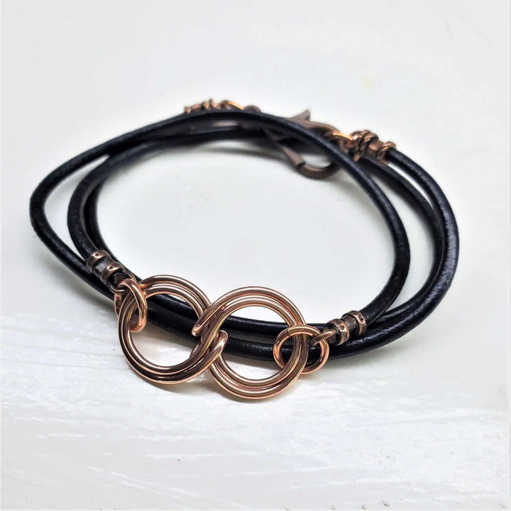 Copper Double Infinity Gender Neutral Leather Wrap Bracelet on black leather cord with intertwined copper symbols.