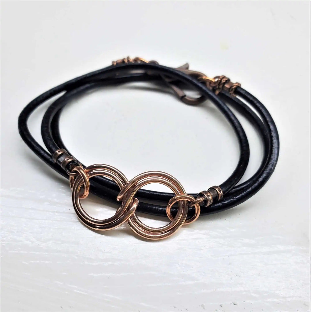 Copper Double Infinity Gender Neutral Leather Wrap Bracelet on a white background featuring black leather and copper-linked design.