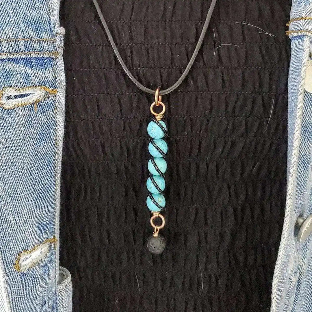 Copper turquoise pendant with lava rock charm worn on a black top with a denim jacket.