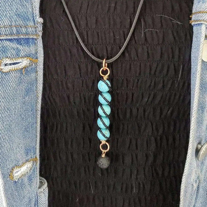 Copper turquoise pendant with lava rock charm worn on a black top with a denim jacket.