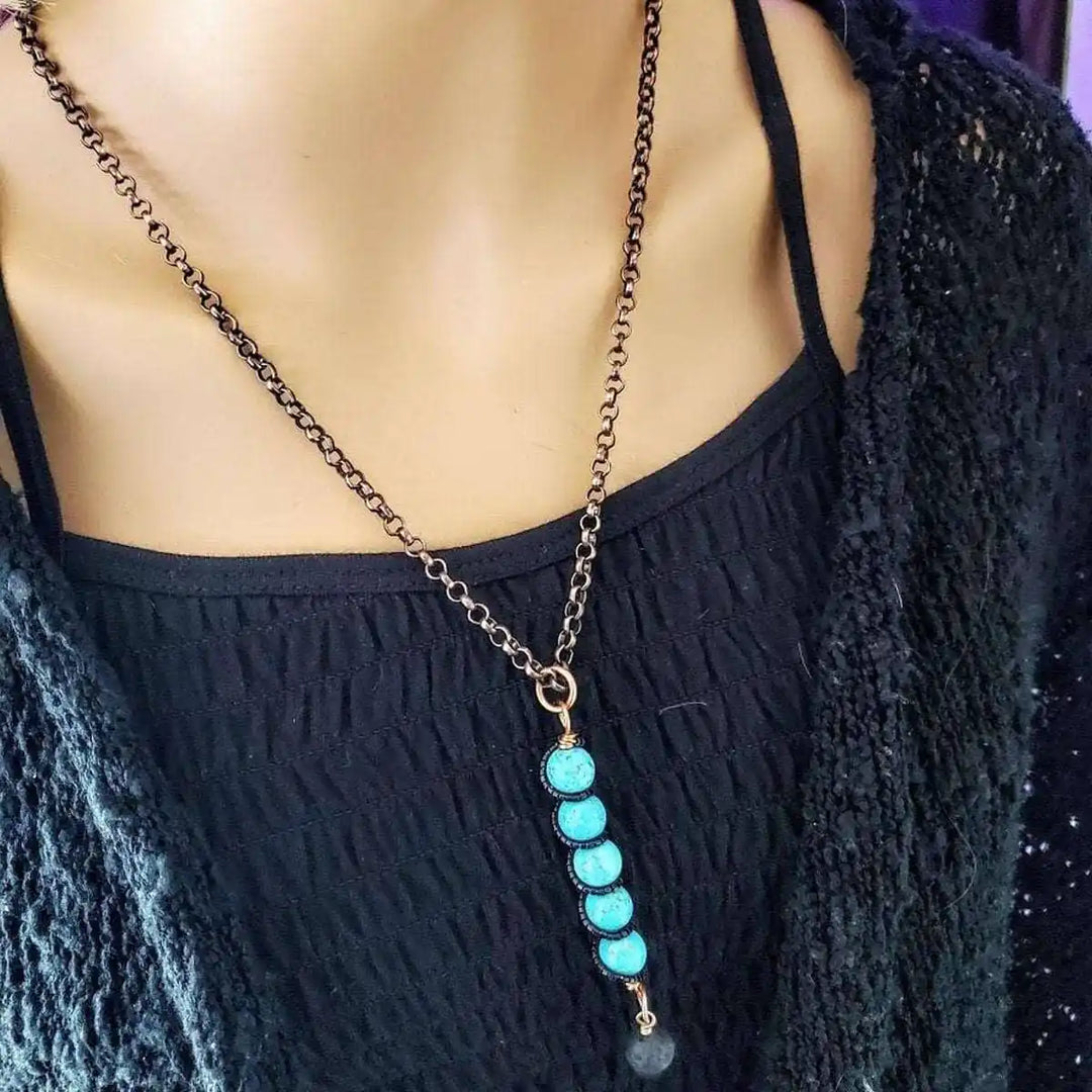 copper turquoise pendant with lava rock charm worn on a black top, showcasing artisan craftsmanship and unique design.