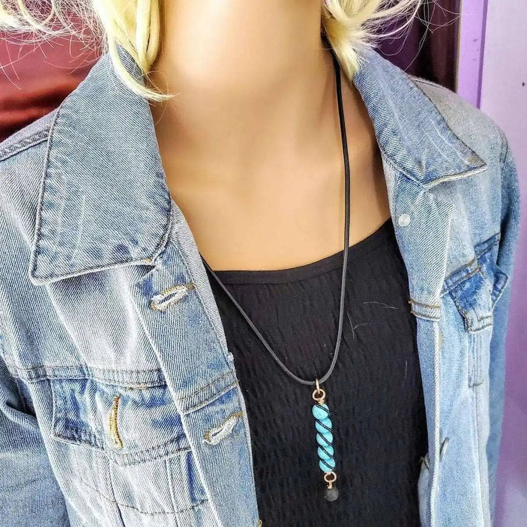 copper turquoise pendant with lava rock charm displayed on mannequin wearing denim jacket