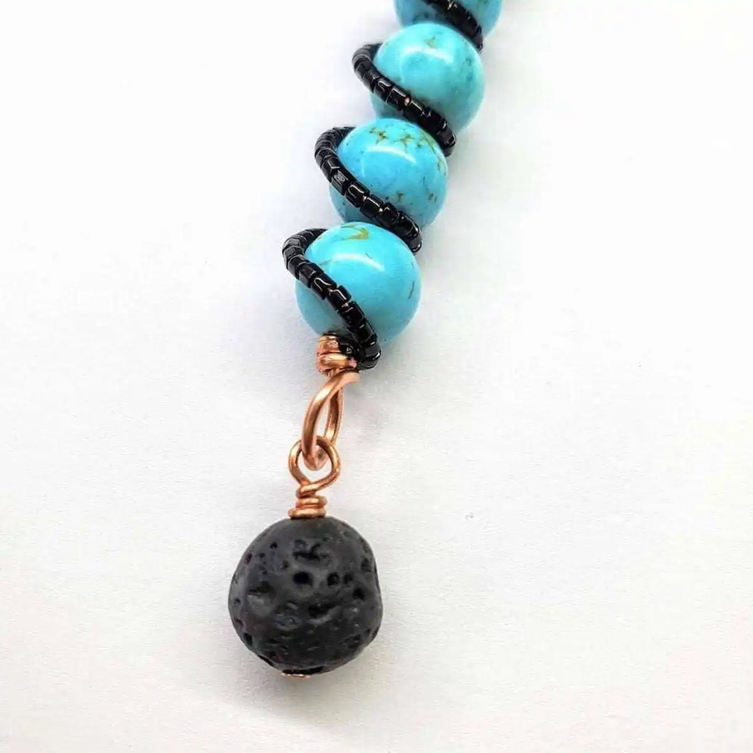 Copper turquoise pendant with lava rock charm showcasing vibrant blue stones and black charm detail.