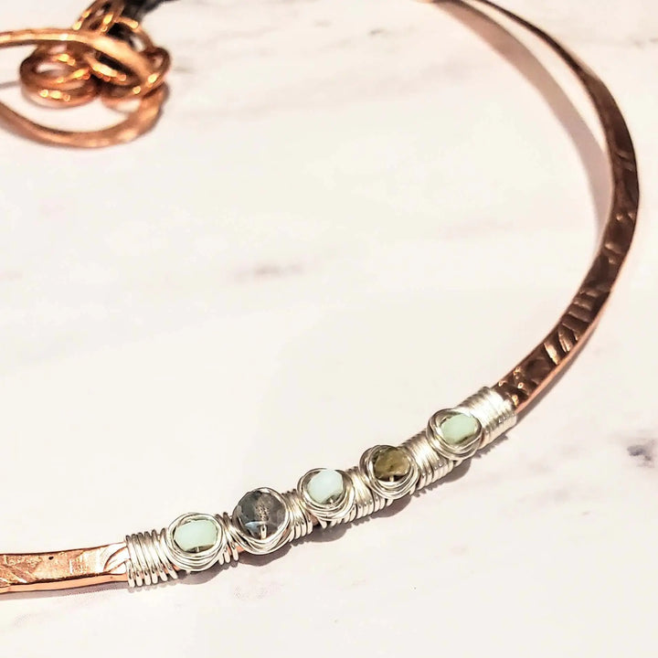 Ergonomic Copper Sculpted Embossed Wire Gemstone Choker showcasing wrapped gemstones on a polished surface.