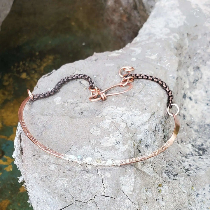 Ergonomic Copper Sculpted Embossed Wire Gemstone Choker displayed on a rocky surface with a unique design.