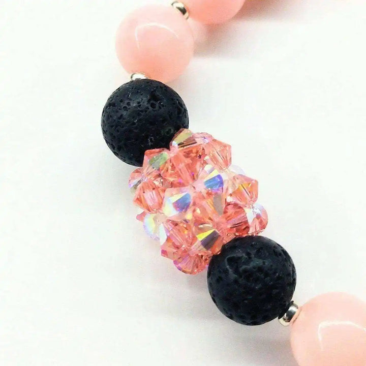 Close-up of Peach Corral Jade Gemstone Crystal Lava Rock Bracelet with pink and black beads.