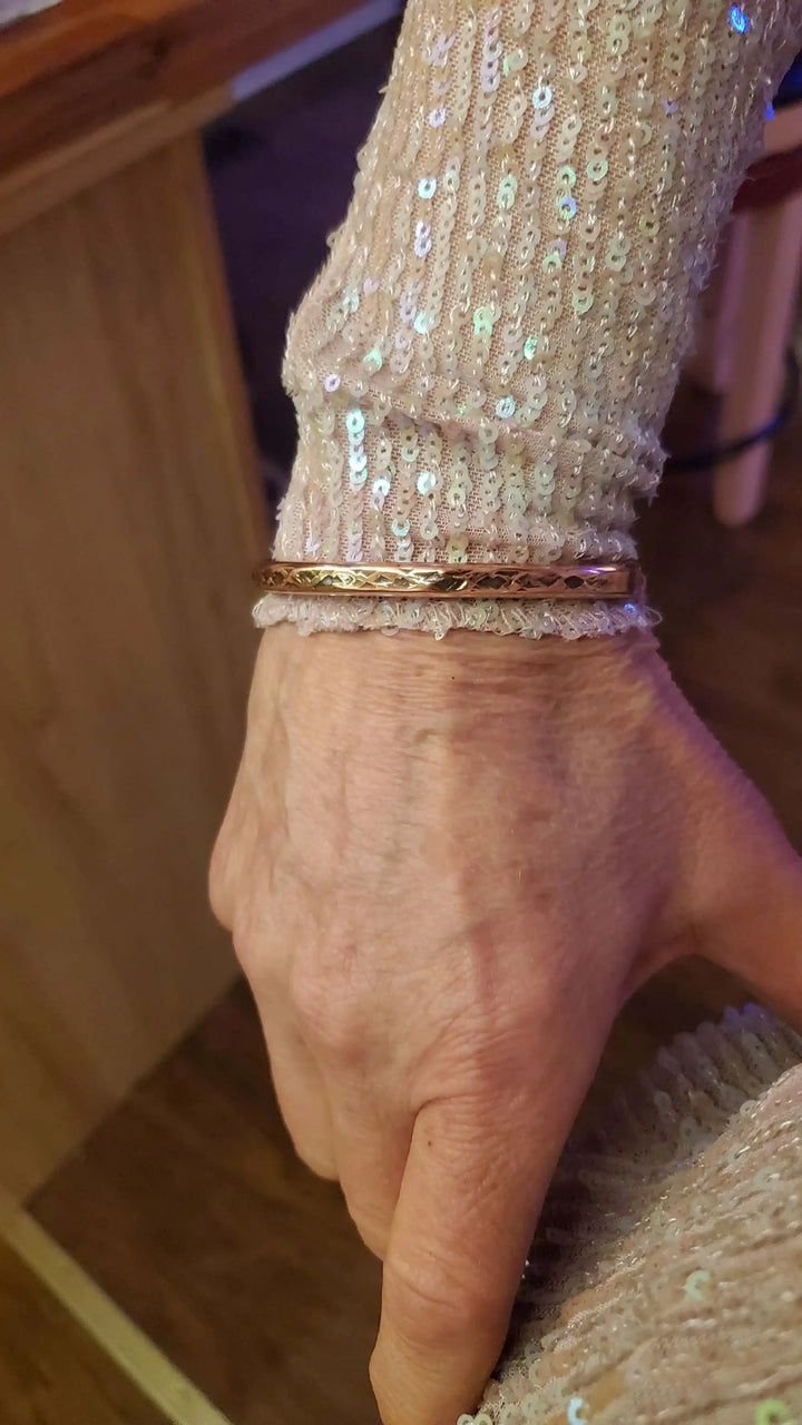 Handmade 2 ounce 6 Gauge Copper Hammered BIGGA Bangle worn on a hand with a sequined sleeve.
