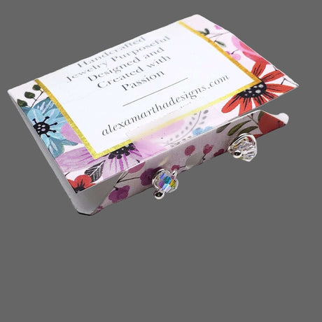 4mm handmade silver crystal spiral ear studs displayed in a beautifully designed gift box with floral patterns.