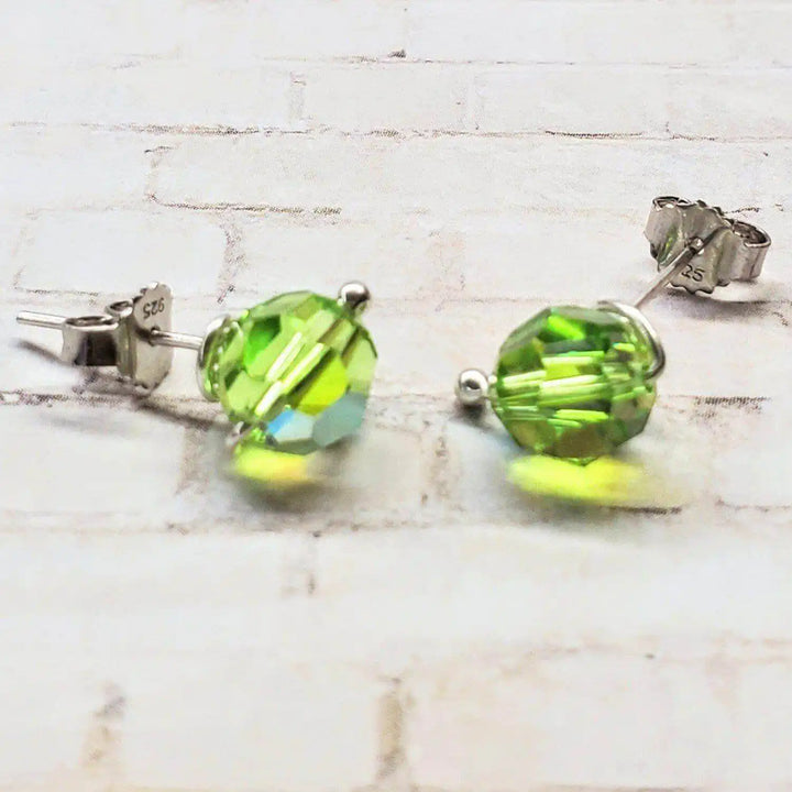4mm handmade silver crystal spiral ear studs shimmering with green Swarovski crystals, showcasing minimalist elegance.